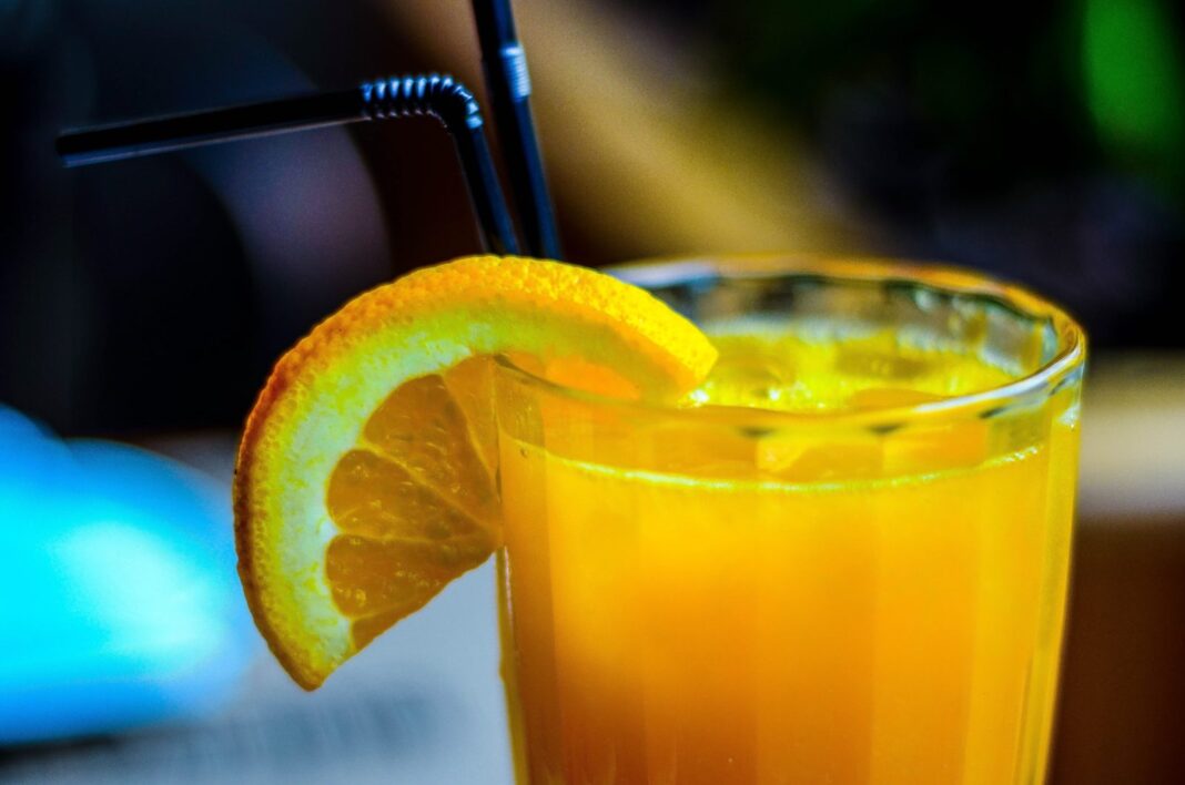 orange juice in drinking glass with slice orange fruit garnish